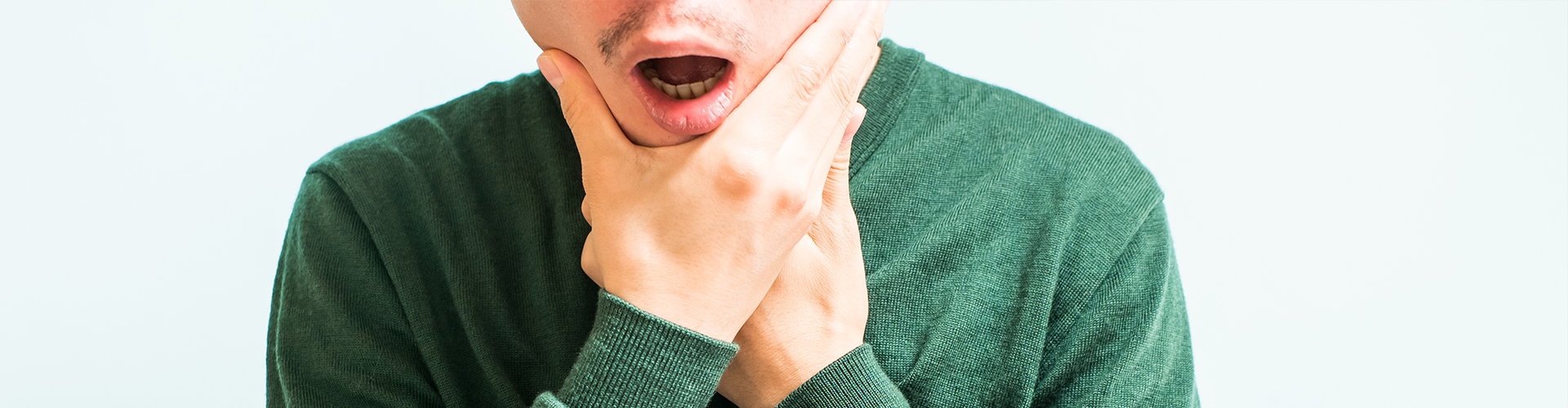 man holding his jaw in pain.