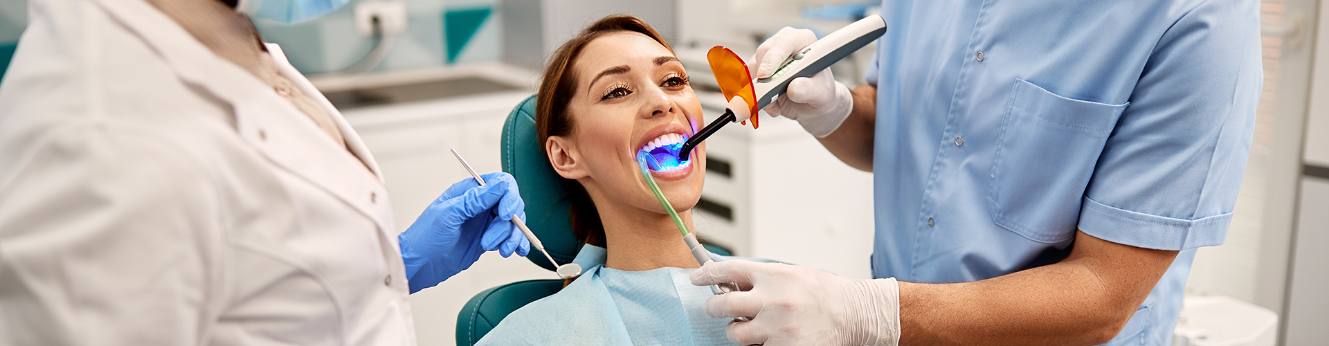 dentist shining led light into patient's mouth.