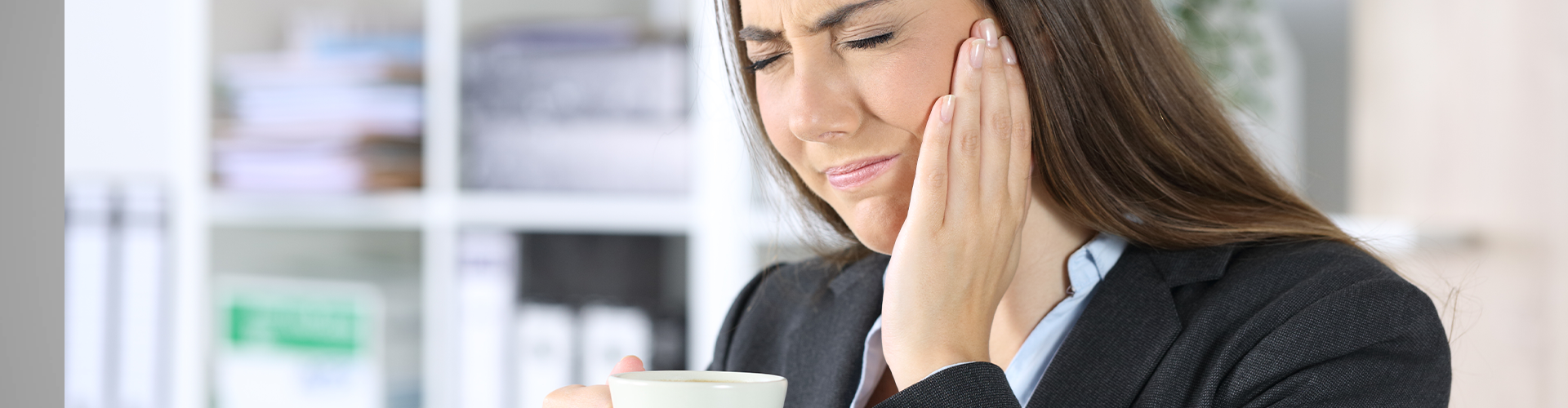 woman holding cheek in pain.