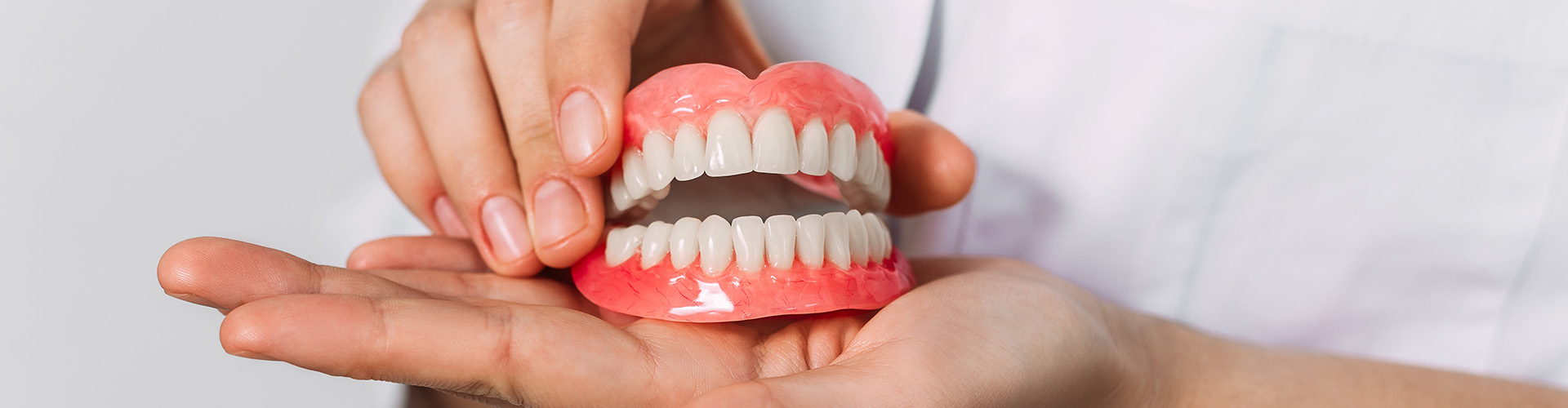 pair of hands holding a set of dentures.