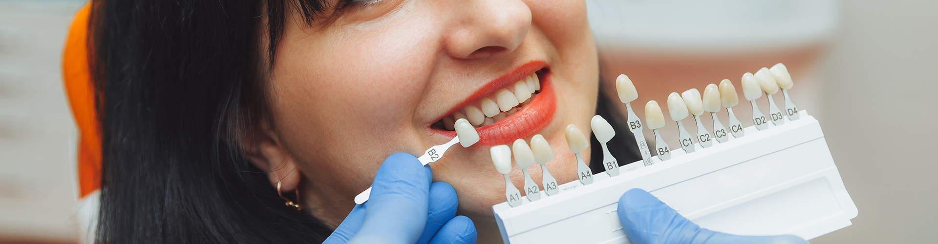 dentist color-matching teeth of smiling woman.