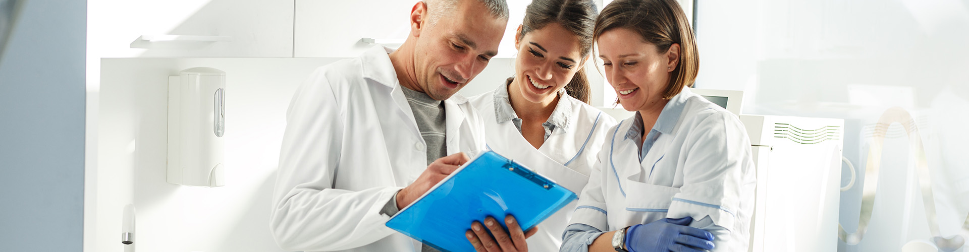 3 member dental team studying clipboard.