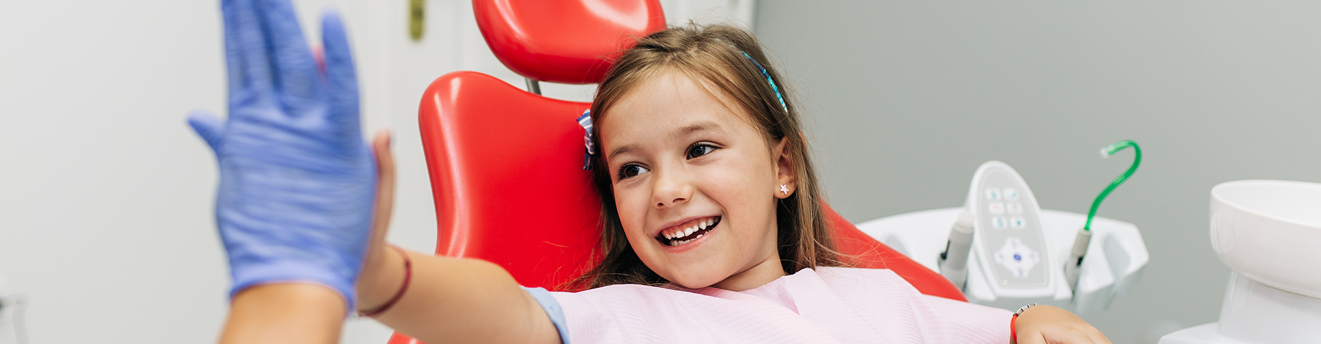dentist high-fiving girl holding teddy bear.