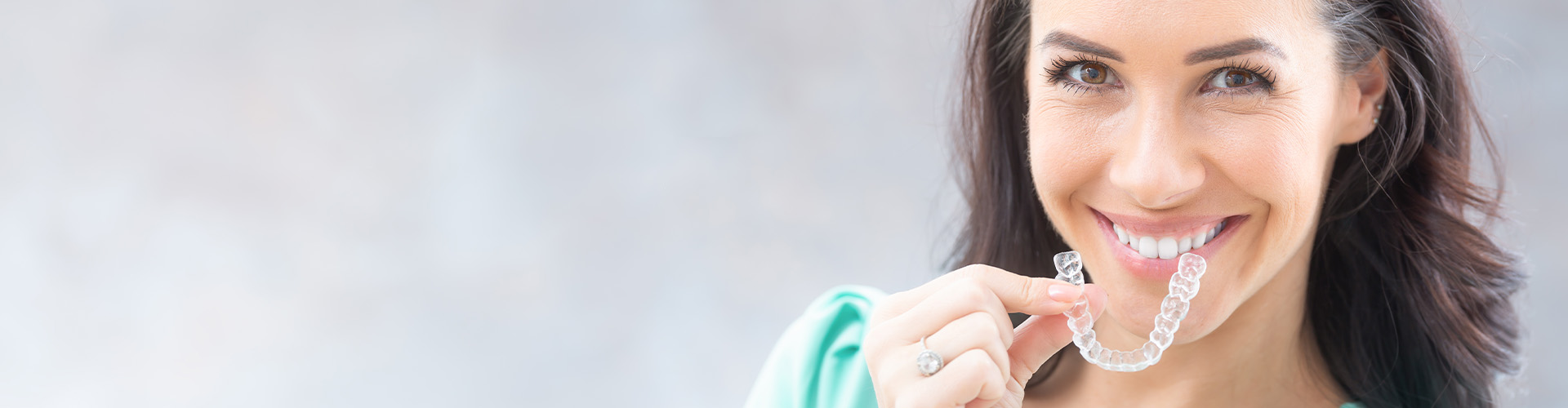 smiling woman holding clear aligner.
