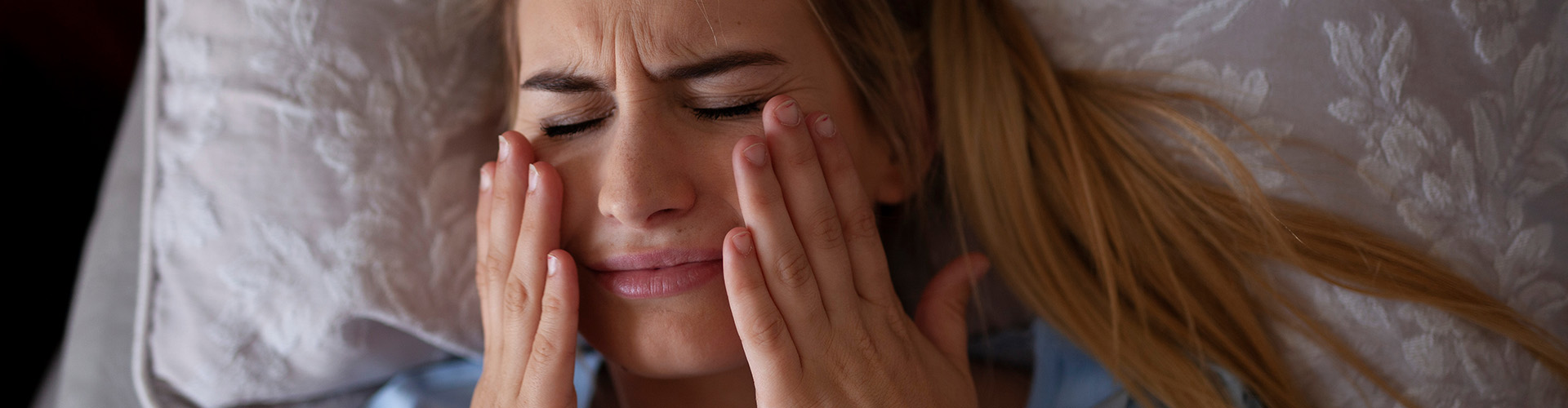 woman holding her face in pain.