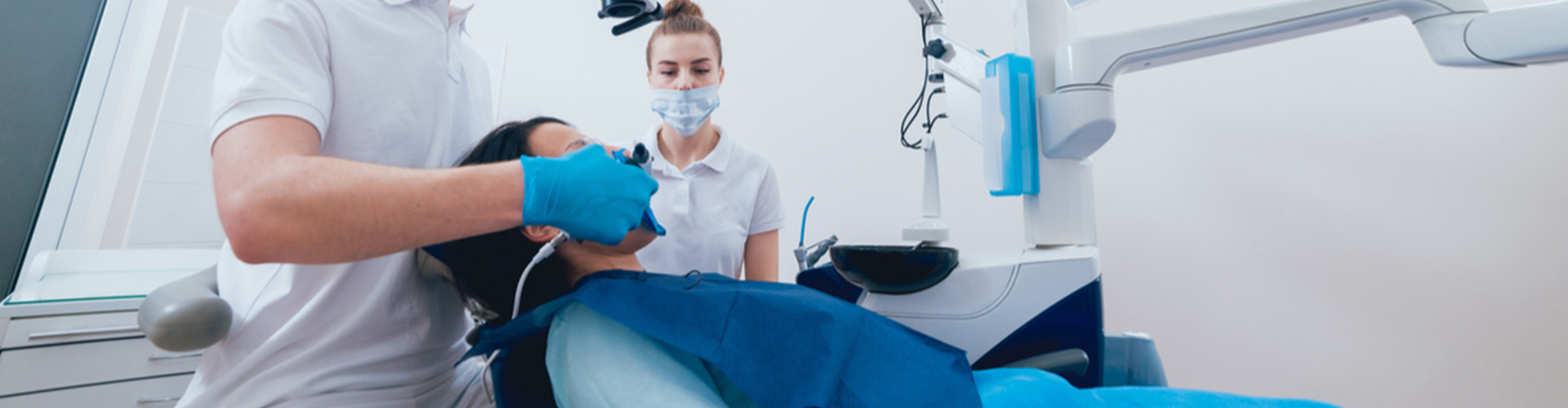 patient in dental chair receiving treatment from dental staff.