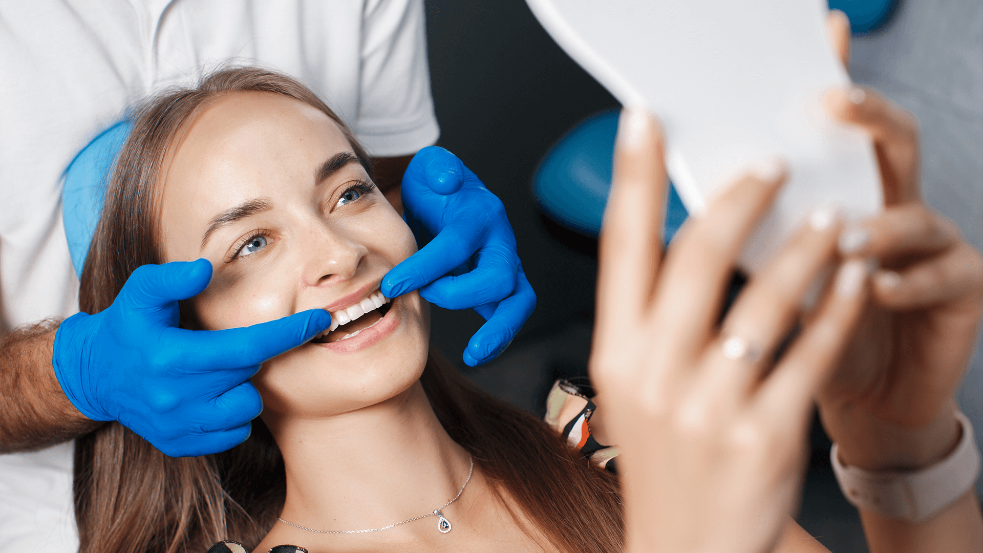 Woman looking in mirror smile and dentist pointing to teeth.