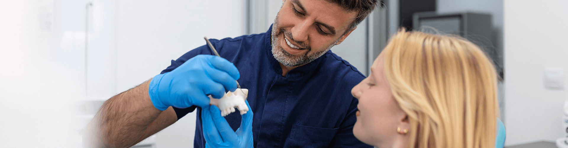 dentist showing patient a mouth model.