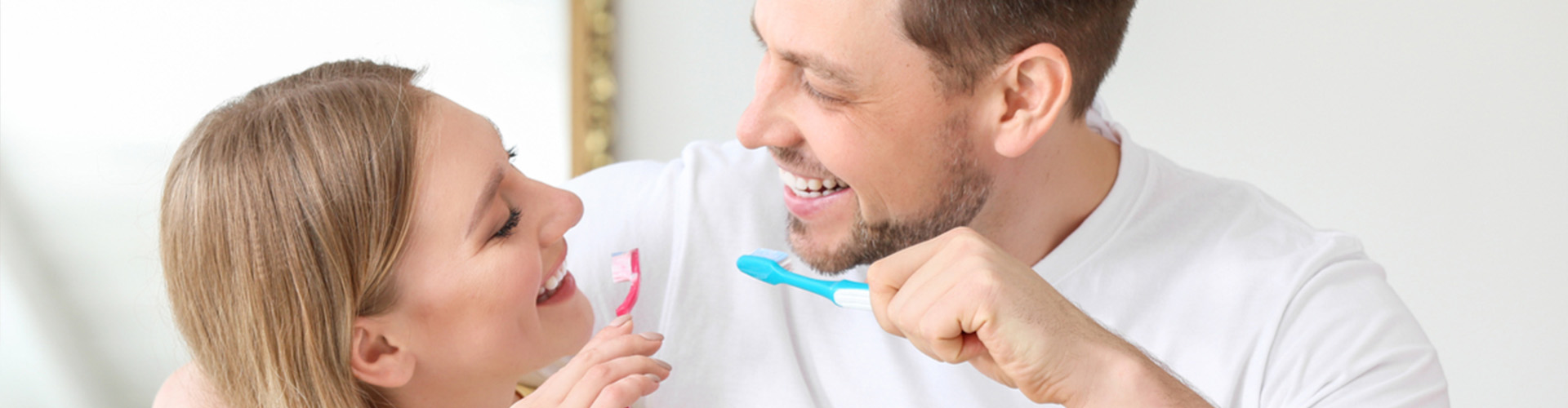 Couple brushing their teeth and smiling together.