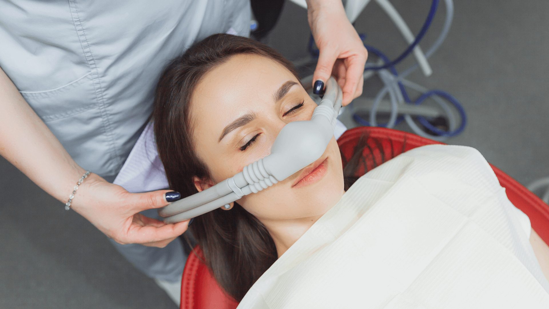 Dentist putting sedation mask on patient.