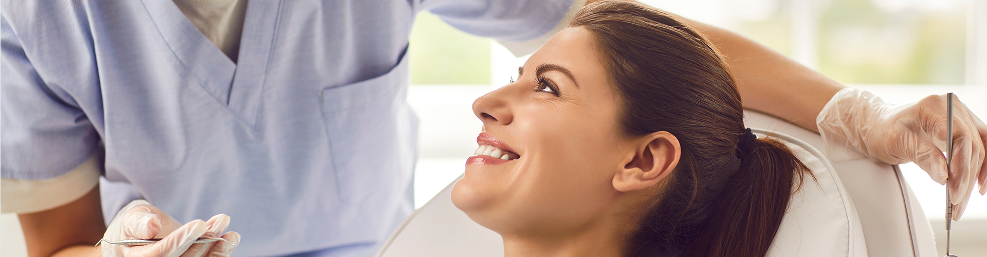 woman smiling up at dentist wearing mask.