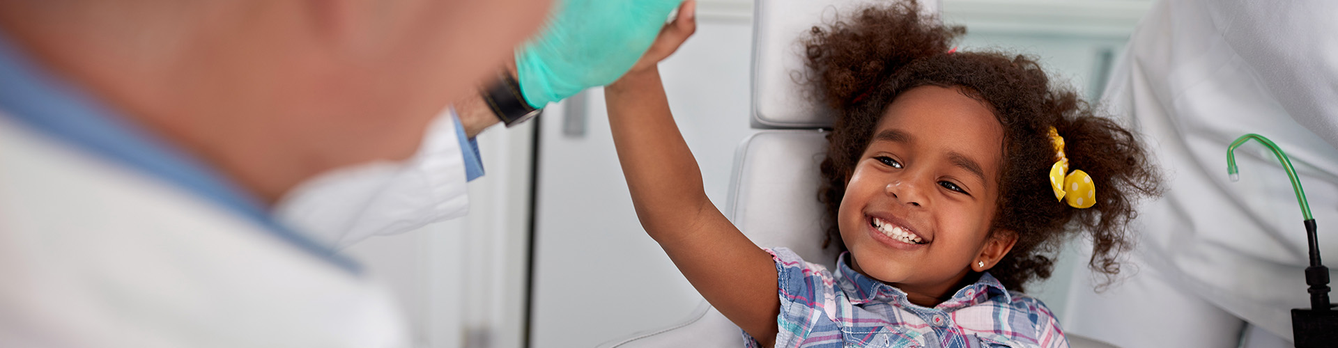 child high-fiving doctor's gloved hand.