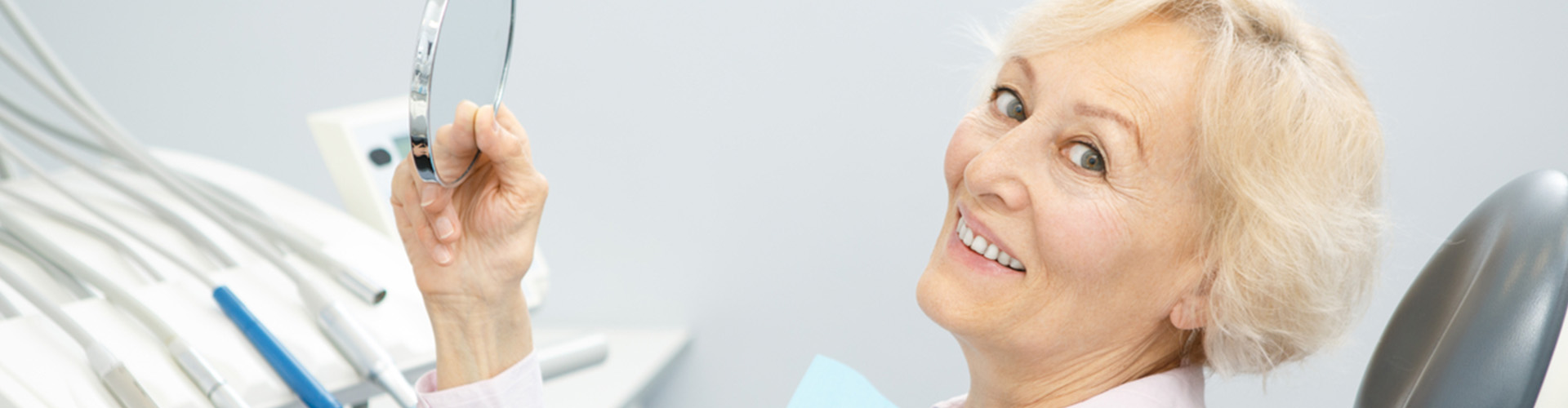 Woman smiling in chair and holding a mirror.