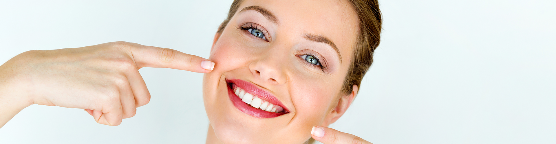 woman pointing at her smile with both hands.