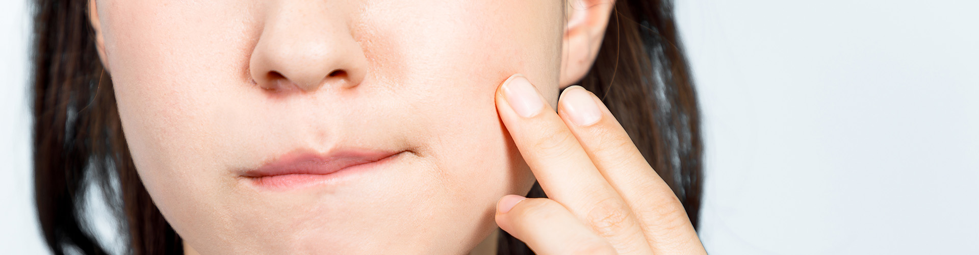 woman holding her jaw in pain.