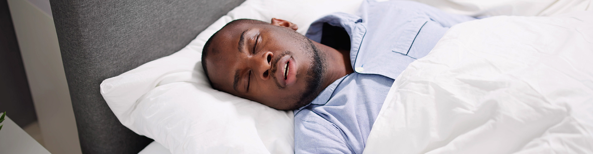 man sleeping on his back in bed.