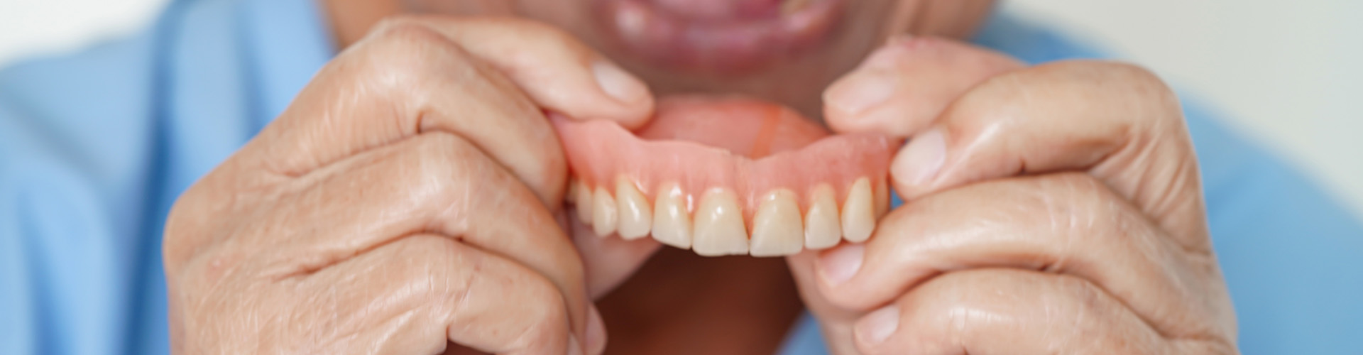 person placing upper denture into mouth.