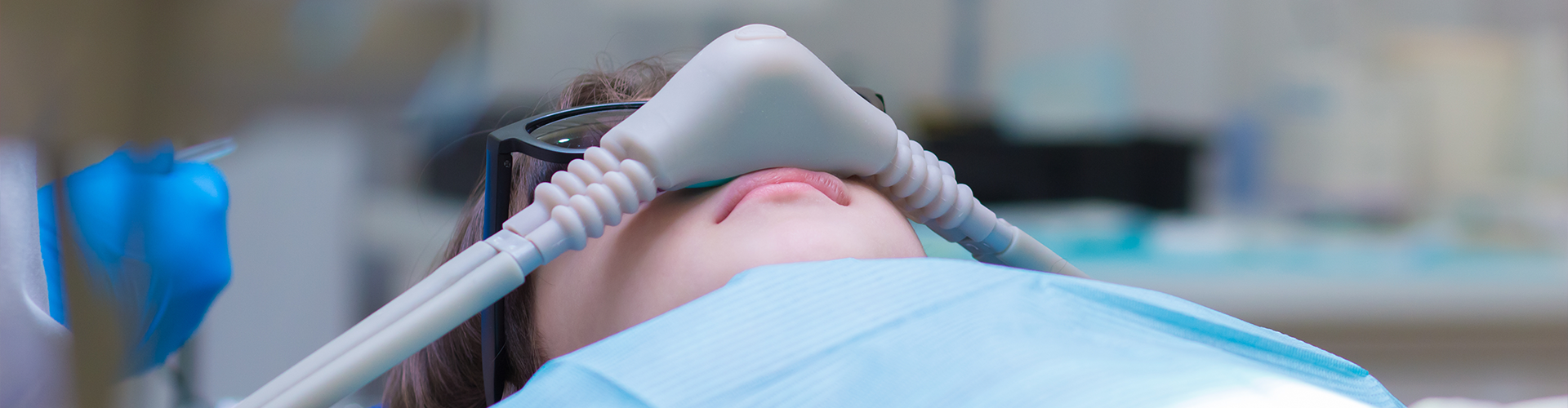 child laying in dental chair with breathing mask over mouth.