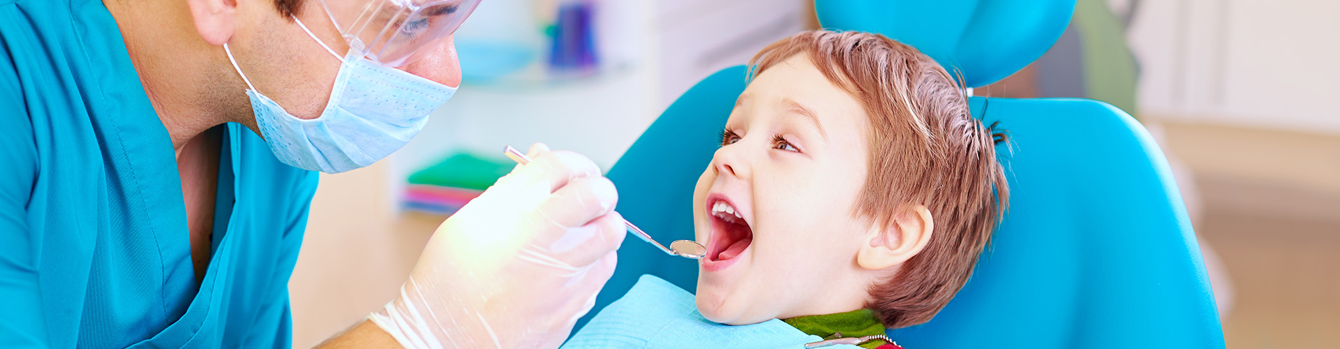 dentist placing dental tool in boy's mouth.