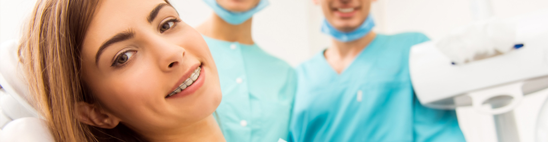 girl smiling with braces in front of dental staff.