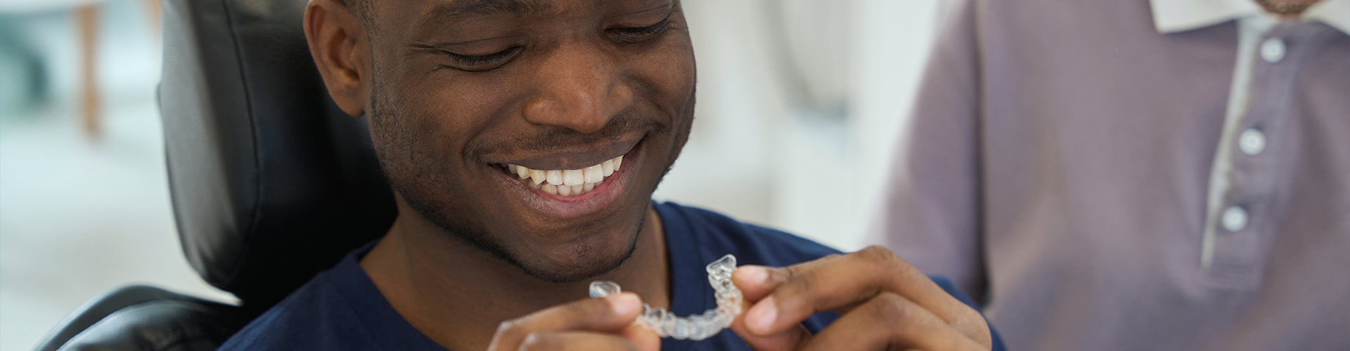 smiling man holding clear aligner.