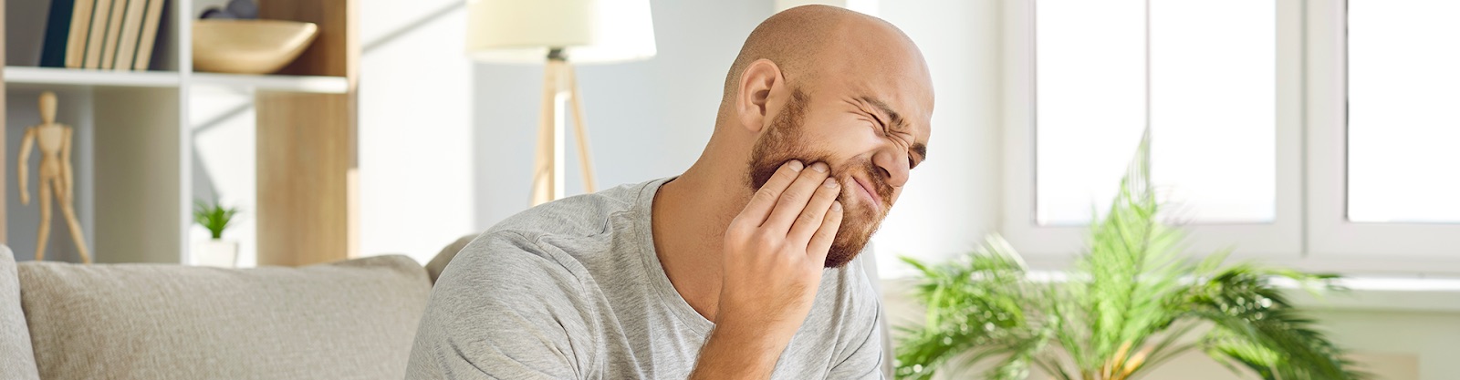 man holding cheek with a pained expression.