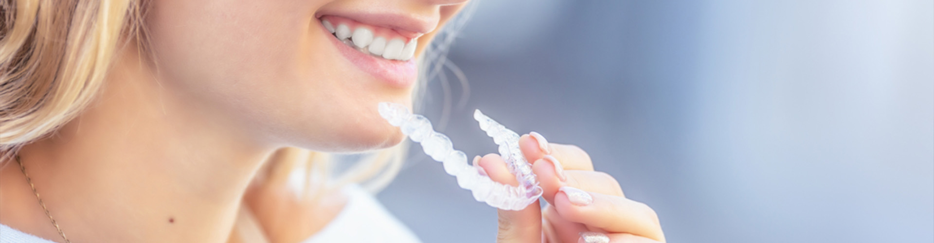 smiling female holding clear aligner.